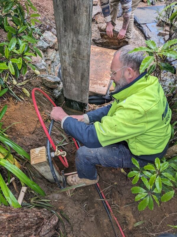 Garden tap on a post on an outdoor shower supply trench