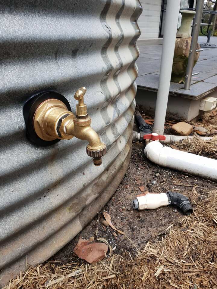 Brass outlet tap and bulkhead fitting installed through the wall of a corrugated steel rainwater tank